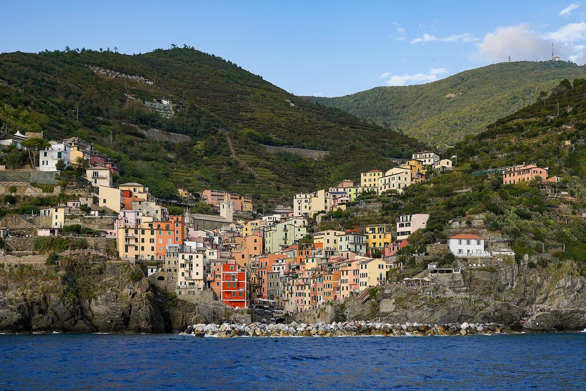 Riomaggiore vista dal mare: le case color pastello che scendono a cascata verso il piccolo approdo.