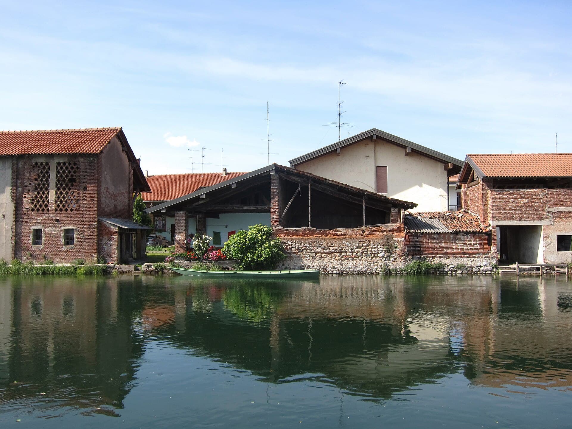 Una barca ormeggiata lungo il Naviglio Grande tra vecchie case di mattoni, l'anima più tranquilla e meno fotografata dei Navigli.