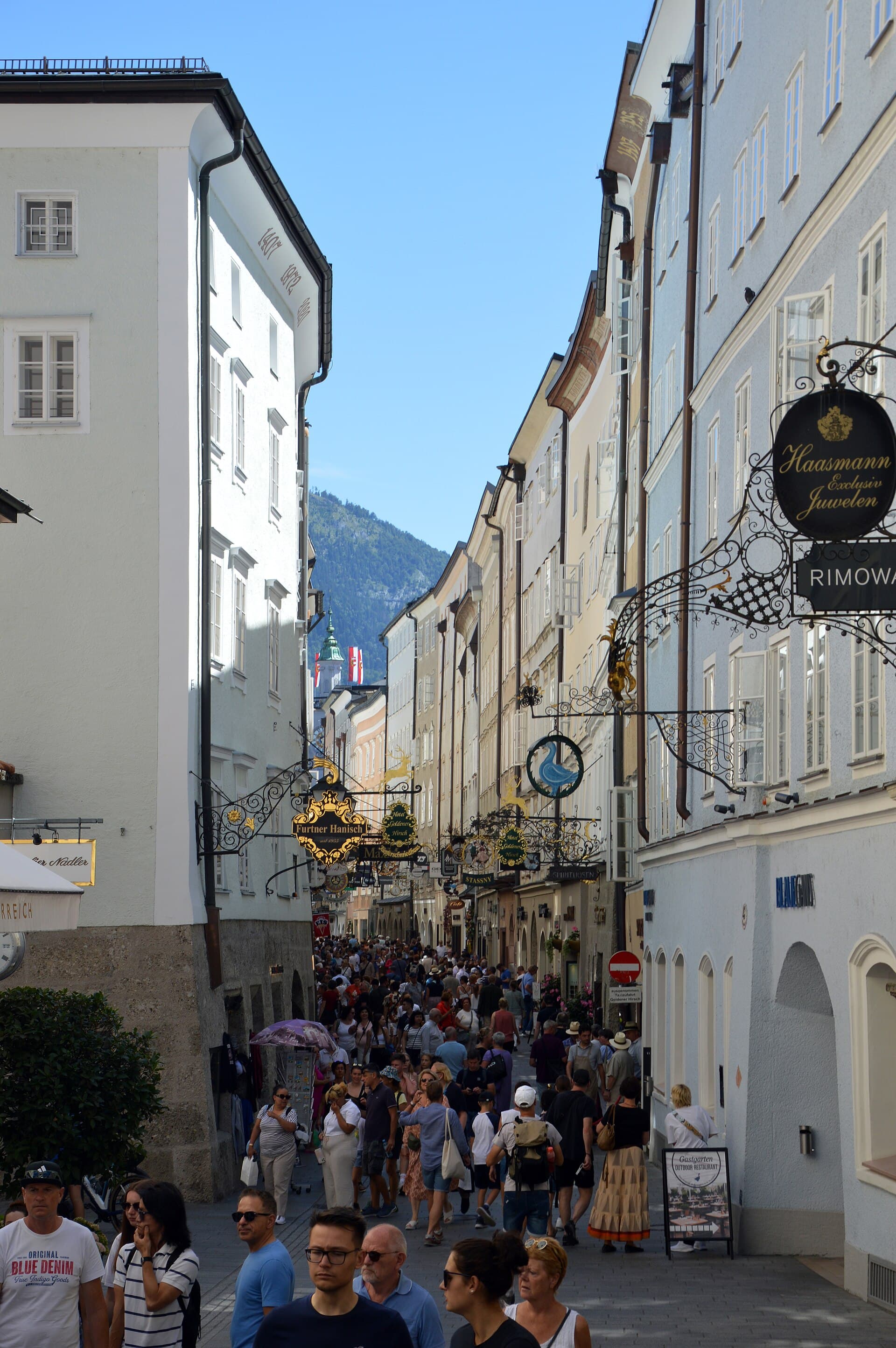 La Getreidegasse gremita, con le sue insegne in ferro battuto sospese sopra le botteghe: la via più famosa della città vecchia, dove nacque Mozart.