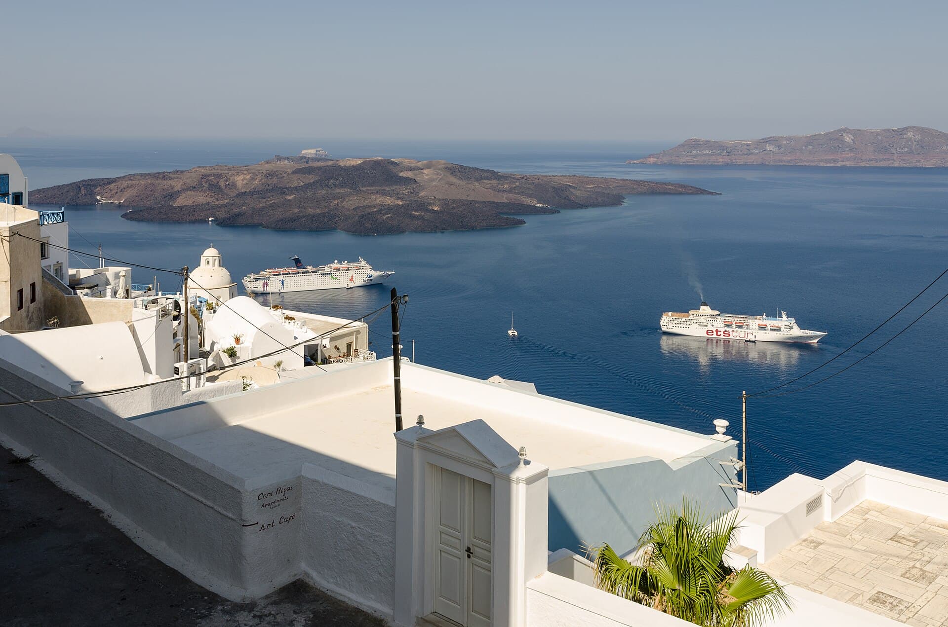 Fira affacciata sulla caldera vulcanica, con le navi da crociera in rada: il cuore turistico dell'isola.
