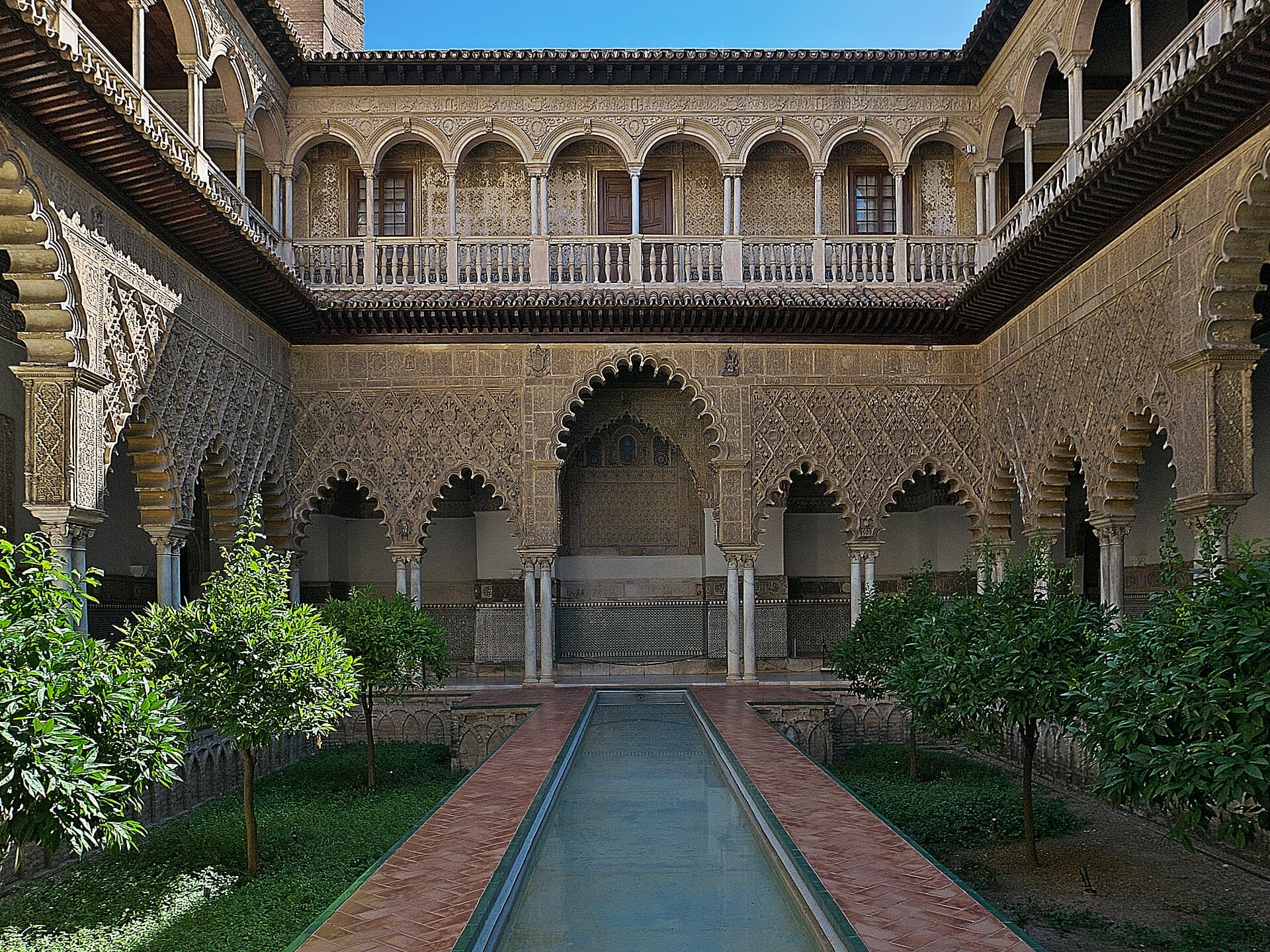 Il Patio de las Doncellas nel Real Alcázar, capolavoro di arte mudéjar con vasca riflettente e giardini di agrumi.