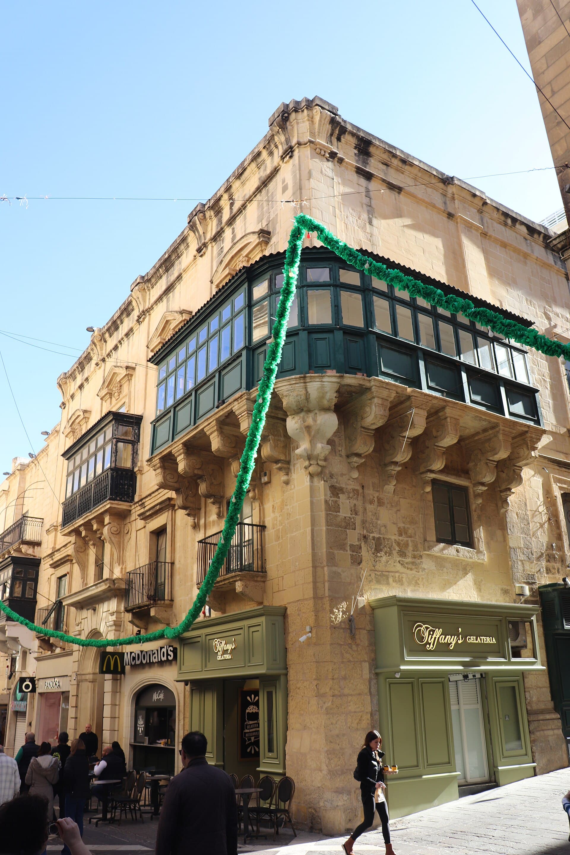 Un angolo di Republic Street con i tipici balconi di legno chiusi (gallarija) sui palazzi color miele: l'immagine-firma delle strade della Valletta.