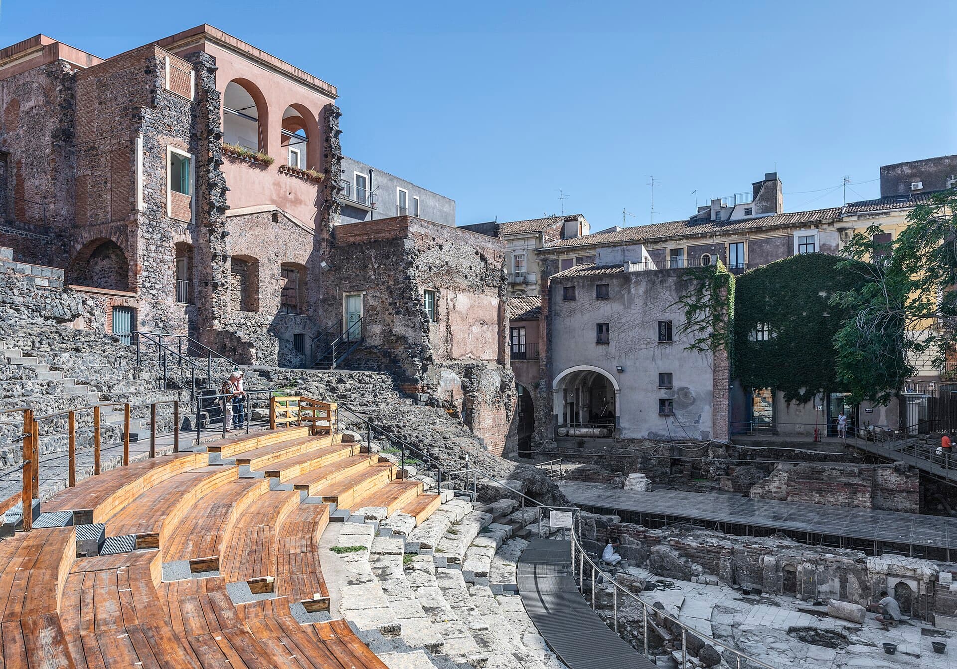 The Roman Theatre wedged between the buildings of Via Vittorio Emanuele: invisible from the street, entered through a doorway.